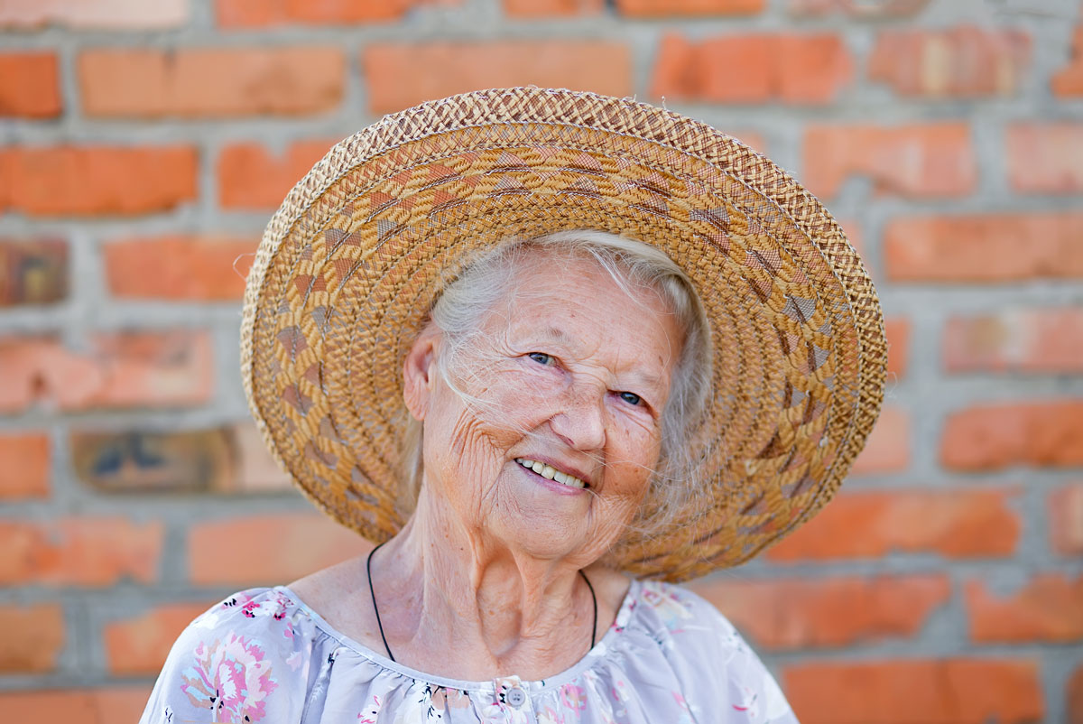 Happy Older Woman with Oxygen Wearing a Straw Hat